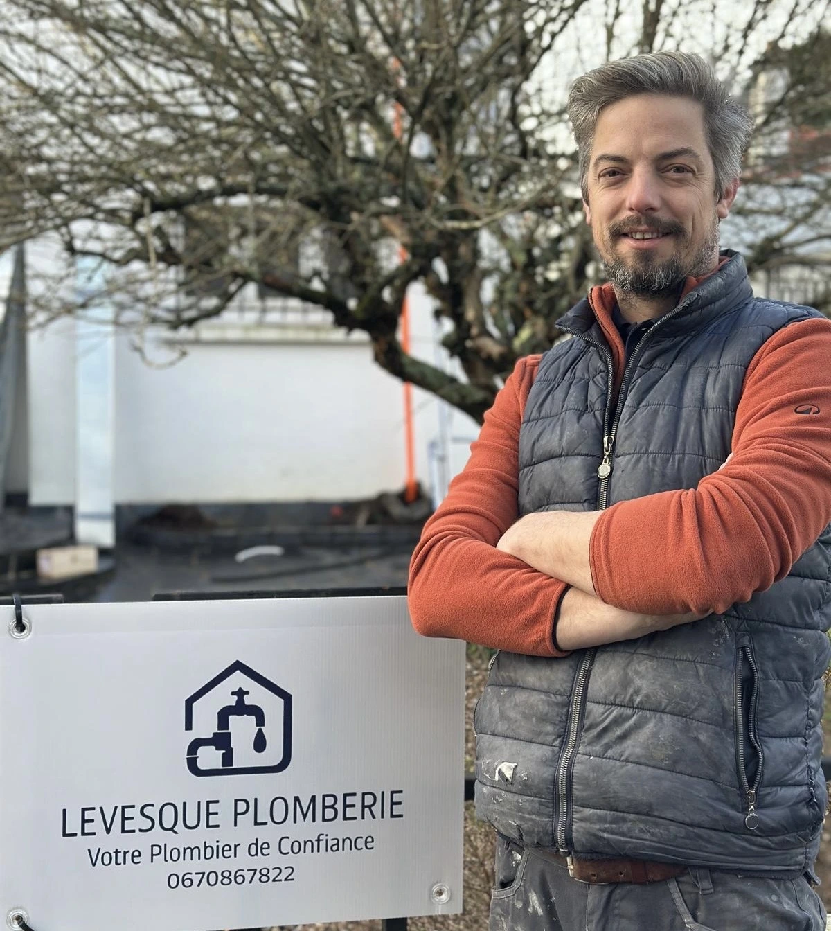 Matthieu Levesque, plombier chauffagiste à Saint-Étienne-de-Montluc, devant le panneau Levesque Plomberie